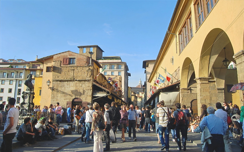 22 - The historic Ponte Vecchio bridge in Florence, Italy, packed with pedestrians walking past its famous cantilevered artisan and jewelry shops